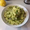 Lemon orzo with zucchini in a bowl garnished with fresh herbs.