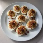 Delicious Million Dollar Bacon Deviled Eggs garnished with crispy bacon.