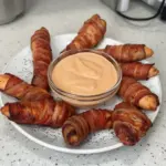 Oven baked bacon wrapped chicken tenders on a serving plate