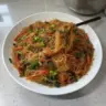 A delicious plate of rice noodle stir-fry with colorful vegetables and sauce.