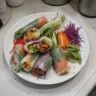Plate of delicious Vietnamese summer rolls with fresh herbs and dipping sauce