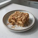 Bowl of delicious apple cinnamon baked oatmeal topped with fresh apple slices and cinnamon