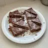 Aussie Crunch chocolate coconut slice on a plate with coconut flakes