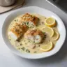 Baked cod fillet topped with coconut lemon cream sauce on a plate