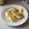 Baked cod fillet served with coconut lemon cream sauce on a plate