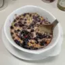 Bowl of blueberry baked oatmeal topped with fresh blueberries and almonds
