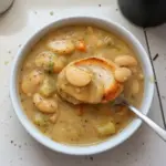 Bowl of creamy butter bean soup garnished with herbs