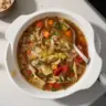 Hearty cabbage soup served in a bowl with fresh herbs and vegetables