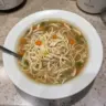 Bowl of Chicken Noodle Feel Better Soup with noodles and fresh herbs