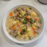 Bowl of classic ground beef potato soup garnished with fresh herbs