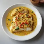 Plate of coconut curry baked cod garnished with fresh herbs