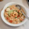 A bowl of Coconut Lime Shrimp and Cod Chowder garnished with fresh herbs.