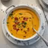 Bowl of creamy carrot soup garnished with fresh herbs