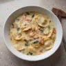 Creamy Tuscan Ravioli Soup in a bowl garnished with herbs