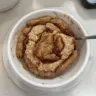 Easy cinnamon roll baked oatmeal in a dish, topped with icing and cinnamon.