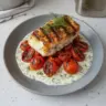 Grilled cod fillet served with roasted tomatoes and creamy dill sauce