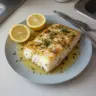 Delicious lemon butter baked cod fillet served with herbs and lemon slices
