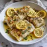 Plate of Lemon Garlic Butter Cod garnished with herbs and lemon slices
