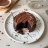 Mini chocolate cake decorated with chocolate frosting on a white plate