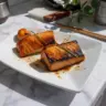 Plate of miso black cod garnished with herbs and served with rice and vegetables.