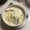 A bowl of New England fish chowder garnished with herbs and served with crusty bread.