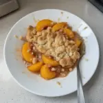 Delicious peach cobbler for two, fresh out of the oven, served in a small dish.