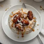 Bowl of salted caramel overnight oats topped with nuts and caramel drizzle