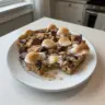 Bowl of S'mores Baked Oatmeal topped with chocolate, marshmallows, and nuts