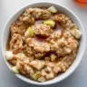 Bowl of spiced pear oatmeal topped with cinnamon and nuts for a healthy breakfast.
