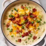 Bowl of tasty loaded potato soup topped with cheese and green onions