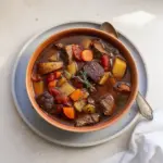 Delicious bowl of venison stew garnished with herbs and vegetables