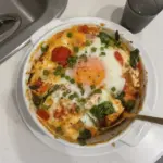Delicious baked feta eggs served with tomatoes and spinach for breakfast