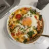 Delicious baked feta eggs served with tomatoes and spinach for breakfast