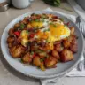 Crispy loaded breakfast hash featuring potatoes, bacon, and vibrant toppings.
