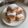 Easy vanilla French beignets dusted with powdered sugar on a plate