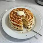 Flourless cottage cheese pancakes stacked on a plate with fresh fruits
