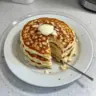 Flourless cottage cheese pancakes stacked on a plate with fresh fruits