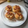 Delicious Maple Bacon Pancake Muffins topped with maple syrup and crispy bacon.