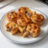 Muffin tin meat pies filled with savory ingredients in a baking tray.
