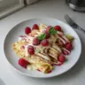 Raspberry Vanilla Cream Crepes topped with fresh raspberries and cream