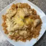 Cheesy chicken and rice dish served in a bowl, topped with herbs.