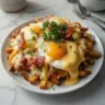 Ultimate breakfast poutine with creamy hollandaise sauce served in a bowl