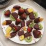 Assorted chocolate dipped fruit on a decorative plate