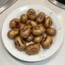 Plate of grilled baby new potatoes garnished with herbs and spices.