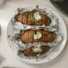 Grilled hasselback potatoes drizzled with chive butter on a serving plate
