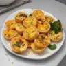 A platter of assorted mini quiches filled with vegetables and cheese.