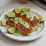 Baked Cajun Salmon served with creamy avocado lime sauce on a plate