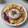 Cranberry Jalapeño Dip served in a bowl with crackers and fresh herbs