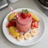 Healthy strawberry banana smoothie in a glass with fresh fruit.