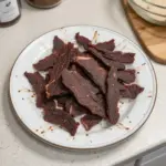 Homemade smoked beef jerky on a wooden cutting board